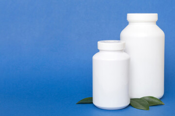 supplement pills with medicine bottle health care and medical top view. Vitamin tablets. Top view mockup bottle for pills and vitamins with green leaves, natural organic bio supplement, copy space