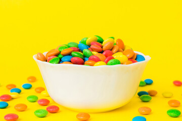 Multicolored candies in a bowl on a colored background. birthday and holiday concept. Top view with copy space