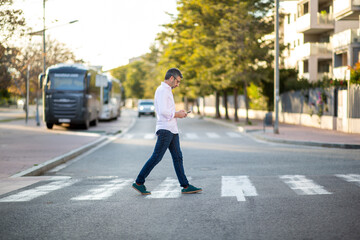 Man crossing street while using smartphone outdoors