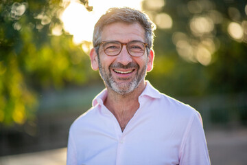 Middle-aged man smiling in pink shirt outdoors