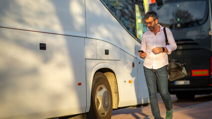 Man walking near buses while using smartphone