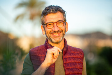 Smiling man with glasses in a park at sunset