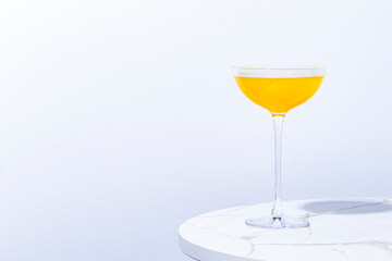 Flying Dutchman, yellow alcoholic cocktail drink with gin, liqueur and lemon juice. Marble table iand white wall