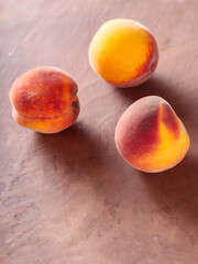 Three Ripe Peaches on Brown Clay Background, Copy Space