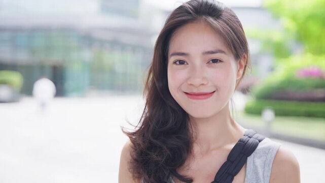 portrait of young asian woman looking at camera smile in the sunny urban city