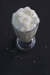 Milkshake in a tall glass with whipped cream and coconut chips