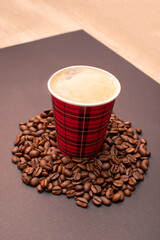 Paper cup with coffee on roasted coffee beans	