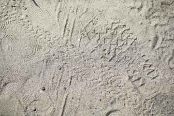 Footprints and Tire Treads on Sandy Beach Surface with Textured Patterns
