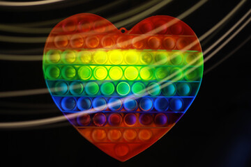 Rainbow Heart-Shaped Pop-It Fidget Toy with Light Trails on Black Background