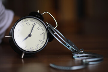 Time and Justice Concept: Alarm Clock Bound by Handcuffs on Wooden Table
