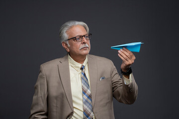 Old Chief Who Has A Serious Expression On His Face Holding Paper Plane In His Hand