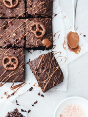 Chocolate Brownies with Pretzel Topping and Caramel Drizzle on White Background and a spoon 