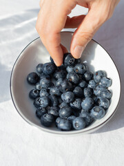 Hand Picking Fresh Blueberries from a Bowl in Natural Light