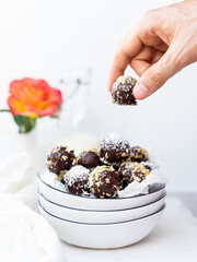 Hand Picking a Chocolate Truffle from a Bowl of Chocolate Covered Truffles with Nuts 
