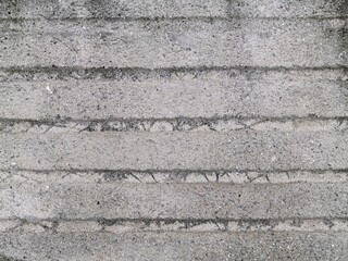Concrete wall with thick horizontal stripes connected by darker dirt