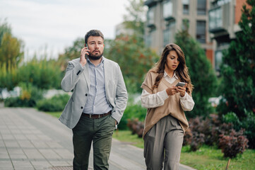 Business people using smartphones while walking on city street