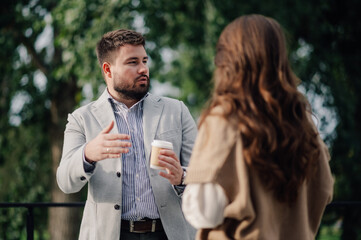 Businessman holding coffee discussing with female colleague outdoors