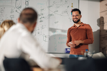 Smiling teacher explaining lesson to students in classroom