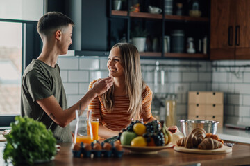 Lesbian couple sharing intimate moment while preparing breakfast in kitchen