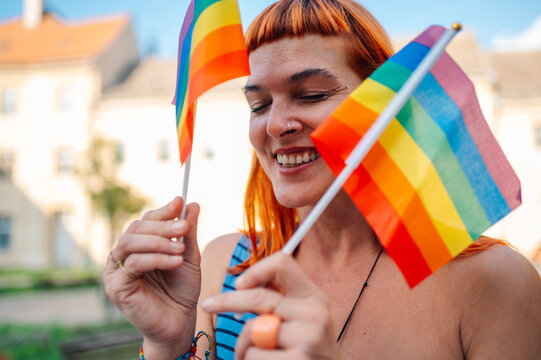 Happy non binary person holding rainbow flags at pride parade celebrating lgbtq rights