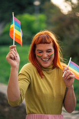 Happy activist holding rainbow flags celebrating lgbtq plus pride in park
