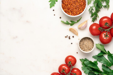 Creative layout of colorful vegetables, greens and spices. Food concept wallpaper. Tomatoes, parsley, arugula, crushed chili, garlic, salt, pepper, dill on white marble background