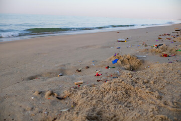 Scraps of paper and plastic are litter on the beach and pollute the environment.