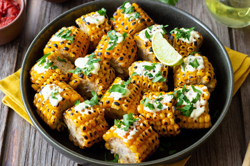 Grilled corn with white sauce and herbs. BBQ. Picnic. Vegetarian food. Diet.