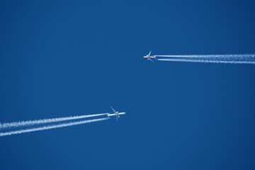 Airplane in the blue sky with contrail. Two planes in the sky.
