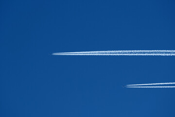Airplane in the blue sky with contrail. Two planes in the sky.