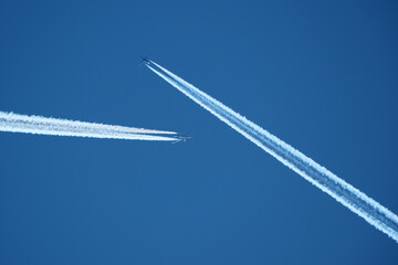 Airplane in the blue sky with contrail. Two planes in the sky.