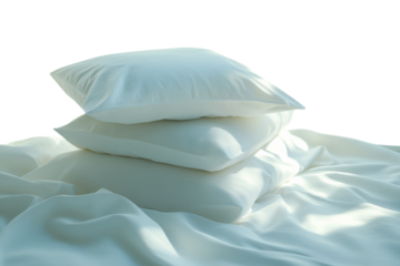 Soft pillows stacked on a cozy white bedding under natural light in a serene bedroom setting