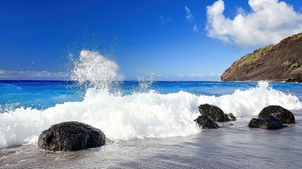 Fototapeta premium Waves crashing on rocky shore under a clear blue sky.