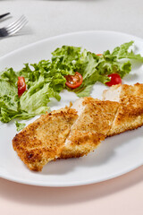 Crisp Chicken Fillet with Cheese Crust and Fresh Salad on Elegant White Plate