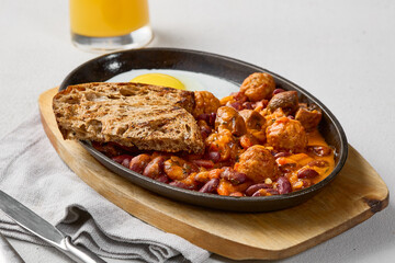 Rustic Breakfast Skillet with Egg, Beans, and Meatballs in Warm Tones