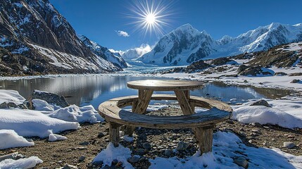 Picnic table by glacial lake with snowy mountains.