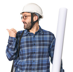 Hispanic male architect with plans points with thumb finger away, laughing and carefree.