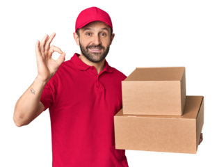 Hispanic male courier with boxes cheerful and confident showing ok gesture.