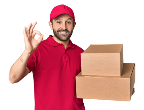 Hispanic male courier with boxes cheerful and confident showing ok gesture.