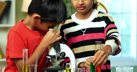 Indian Asian Curious Cute Little Girl and Boy students Sitting at Table in Modern Classroom, Playfully Studying Science Using Microscope, Chemical Solutions in Beakers, Test Tubes learning Chemistry
