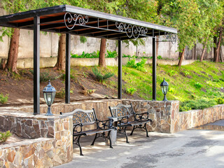 Elegant benches under a stylish canopy in a serene park setting during midday
