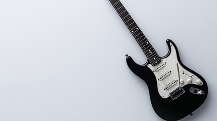 Elegant black electric guitar resting on a white surface indoors