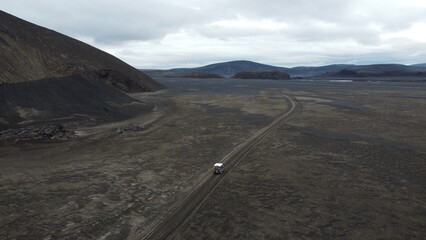 Vue aérienne au drone professionnel d’une voiture en Islande sur route désertique volcanique...