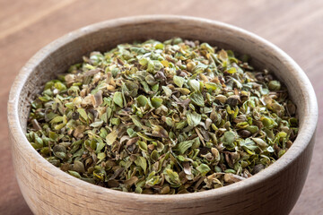 A bowl full of dried and ground organic mountain thyme on wooden table
