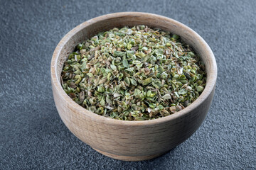 A bowl full of dried and ground natural mountain thyme on gray background.