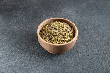 A bowl full of dried and ground natural mountain thyme on gray background.