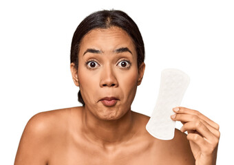 Filipino woman with sanitary pad in studio shrugs shoulders and open eyes confused.