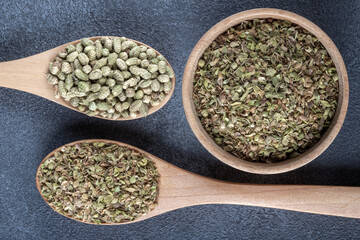A bowl filled with a pile of natural dried thyme seeds, alongside a spoon containing ground thyme