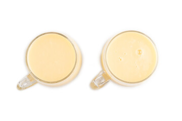 Organic non dairy banana and soy milk in glass isolated on white, top view, close up.