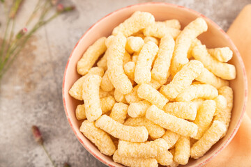 Corn flakes sticks with caramel in ceramic bowl on gray concrete, Top view, flat lay, close up.